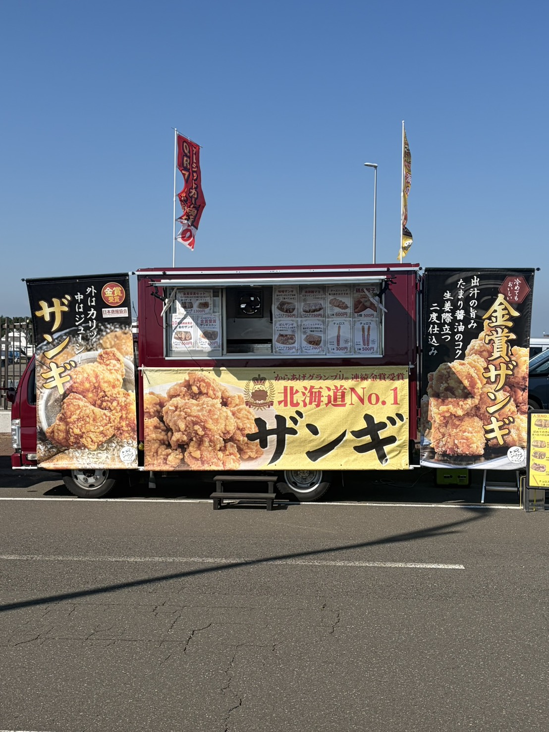 金のザンギの黄色い看板を掲げた実際のキッチンカー、さとちゃん号